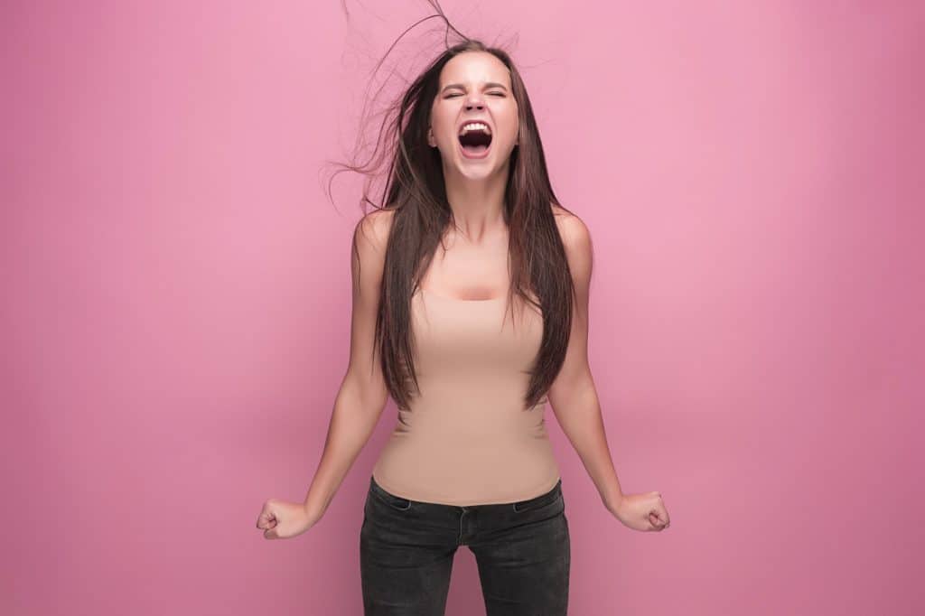 Frustrated young woman screaming at studio